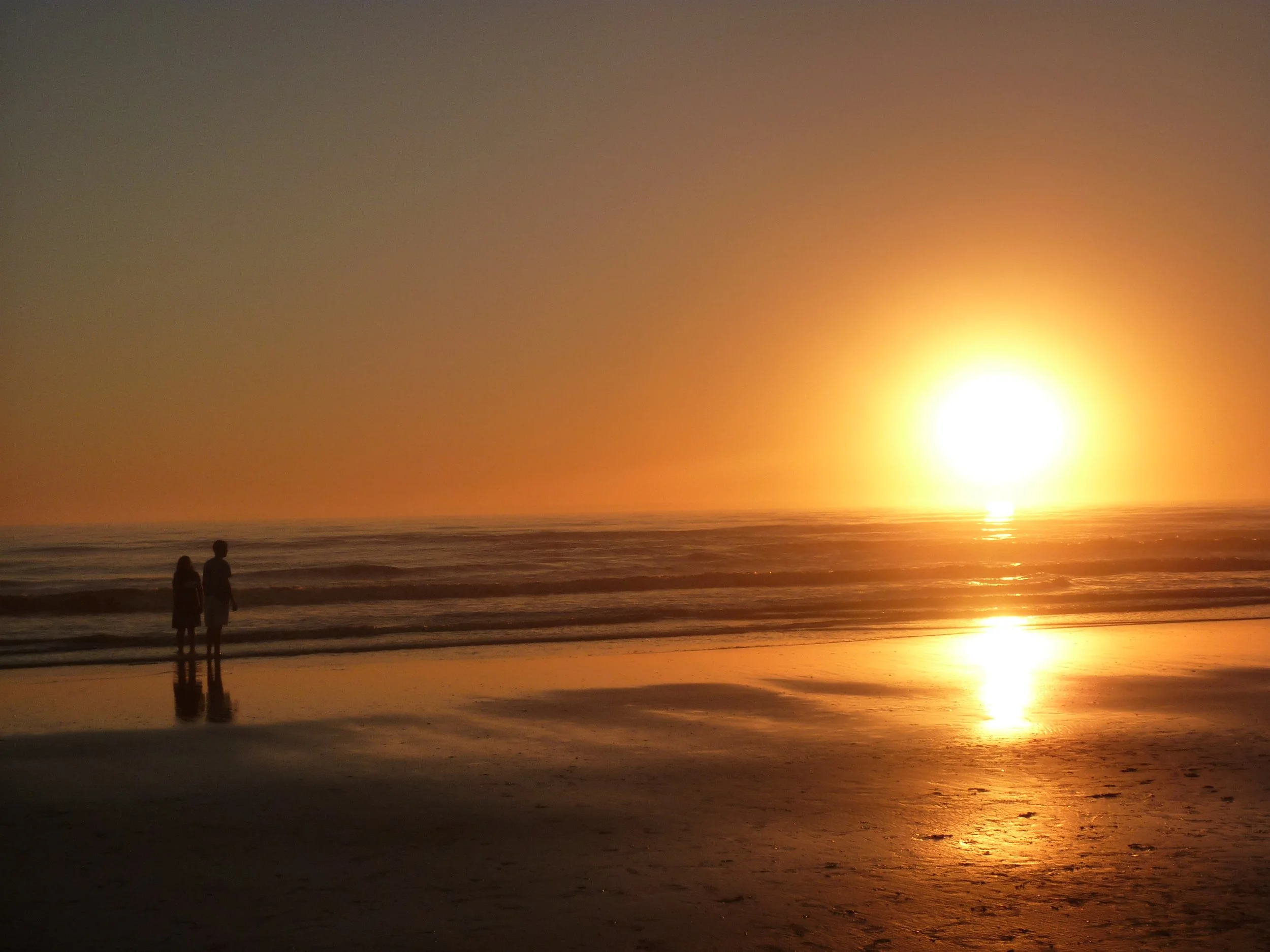 Zwei Personen am Strand bei Sonnenuntergang – Motiv für den Stride Compact (3 Monate Kurzeinsatz in Südamerika oder Spanien)