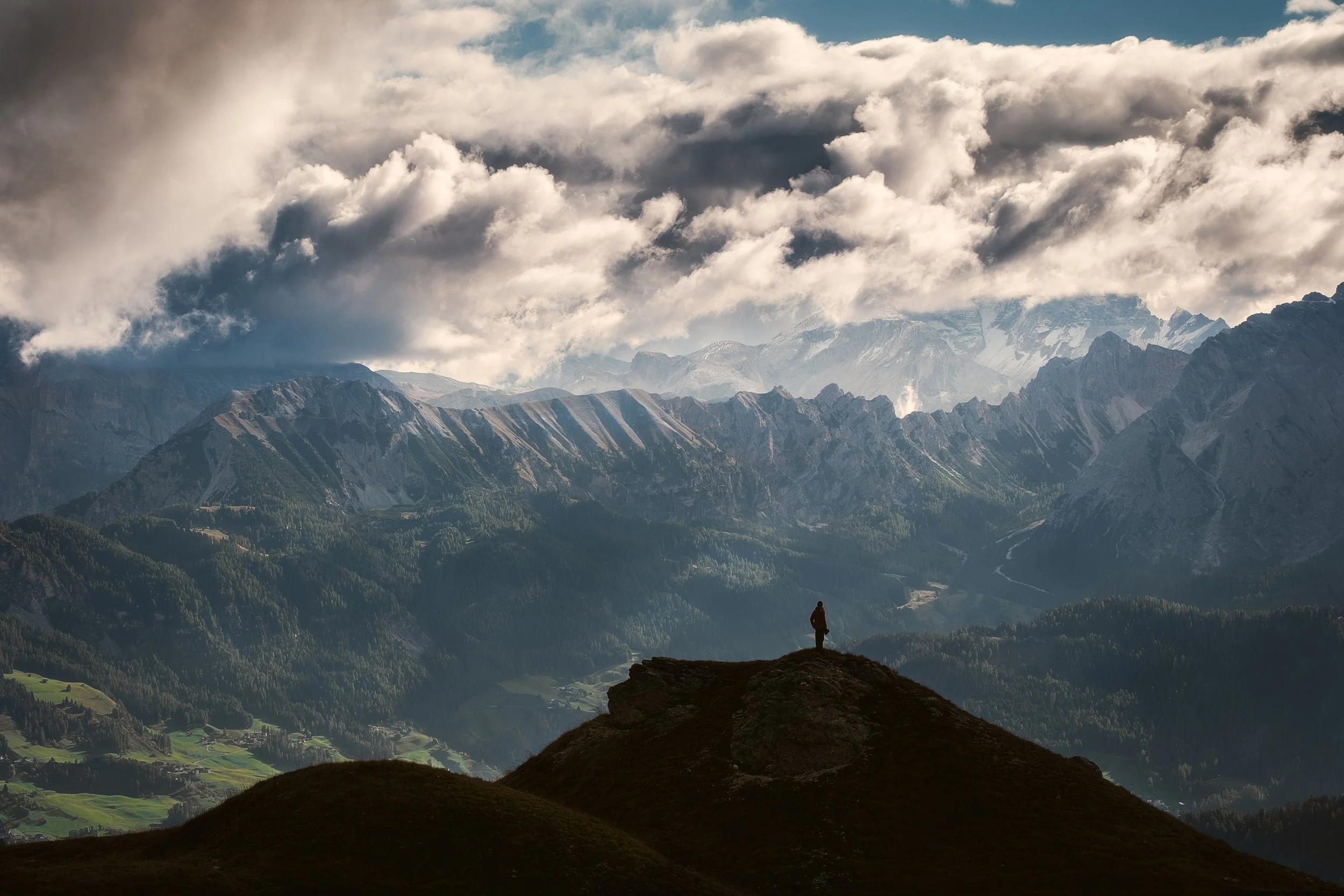 Jagged mountain ridges with hiker silhouted in the foreground.