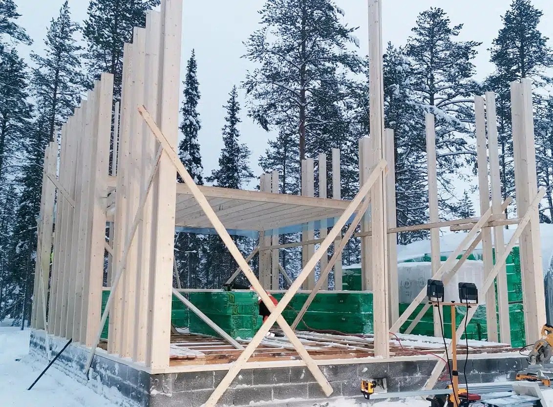 Rakenteilla olevan talon runko talvisessa metsässä.