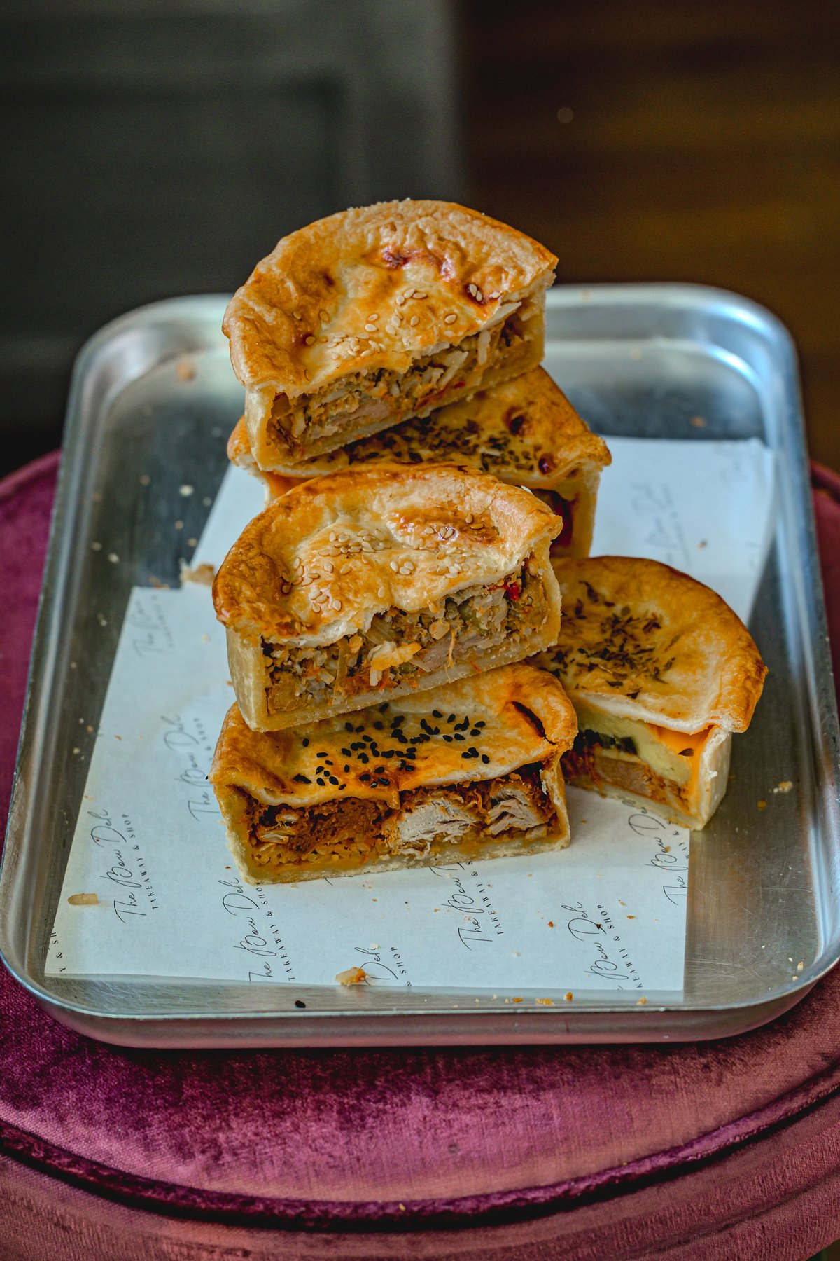 Stack of savory meat pies with crispy crust on a metal tray.