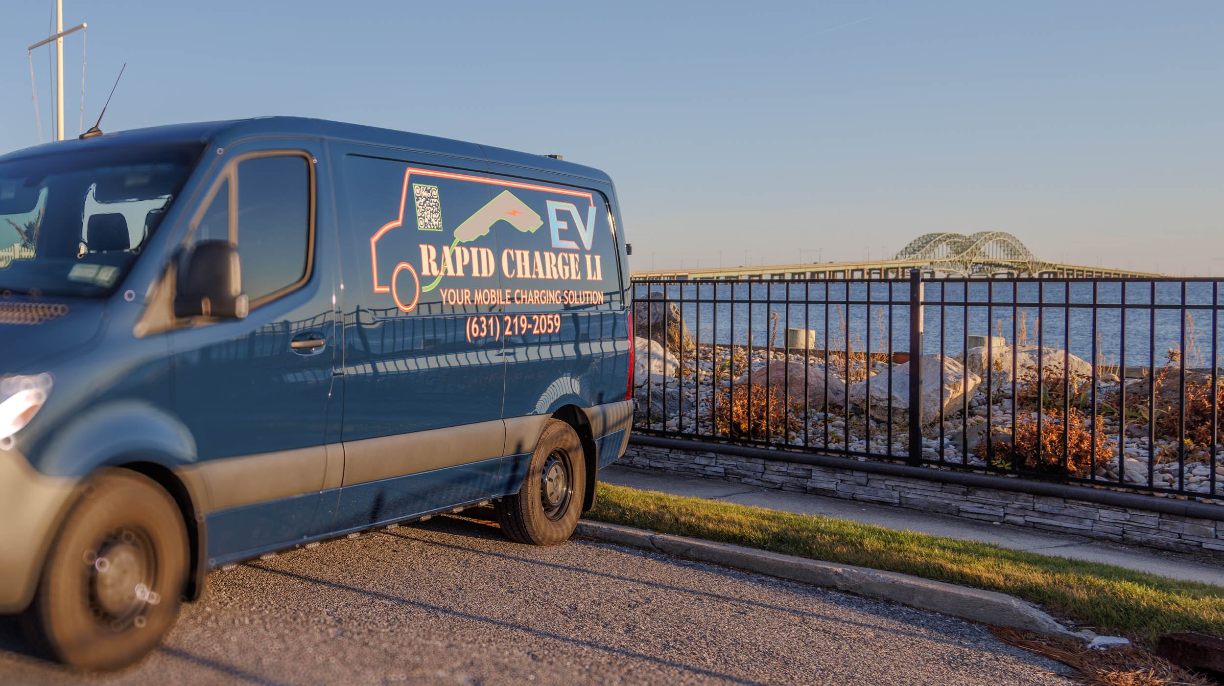 Company van with advertising for EV rapid charging solutions, including a QR code, phone number, and slogan.