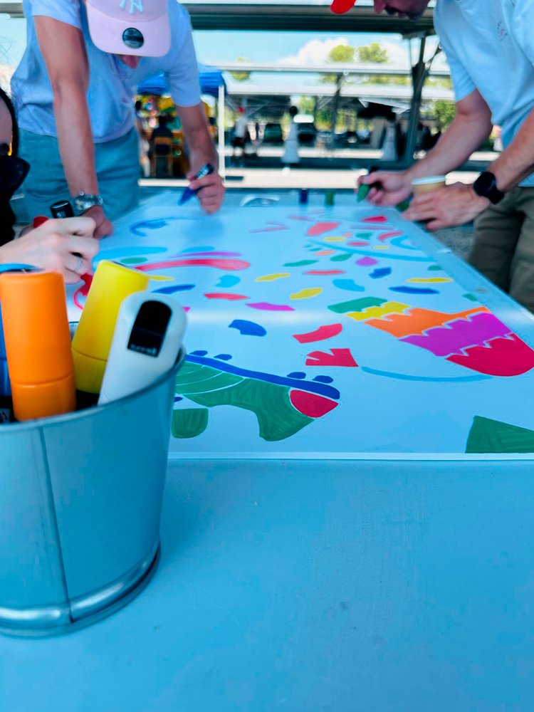 Groupe de participants dessinant ensemble une fresque collaborative avec des marqueurs Posca pendant une activité de team building créatif et un atelier artistique participatif.