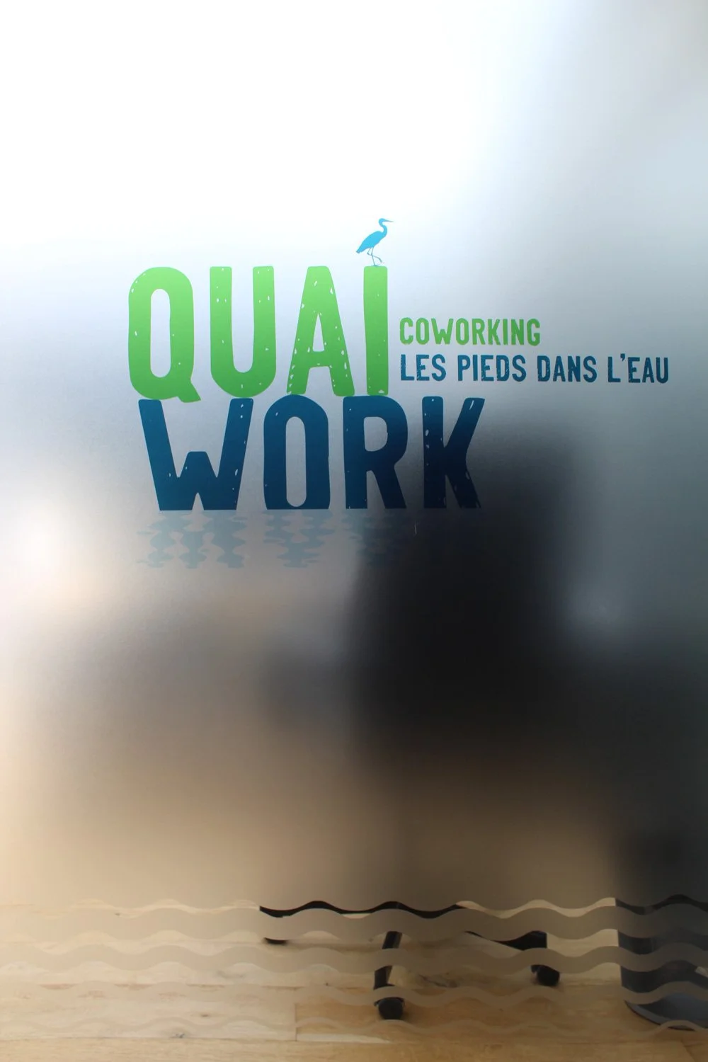 Vitrine de l'espace de coworking Quai Work à Saint-Herblain, ornée de vitrophanie adhésive personnalisée, intégrant le logo et des éléments graphiques distinctifs.