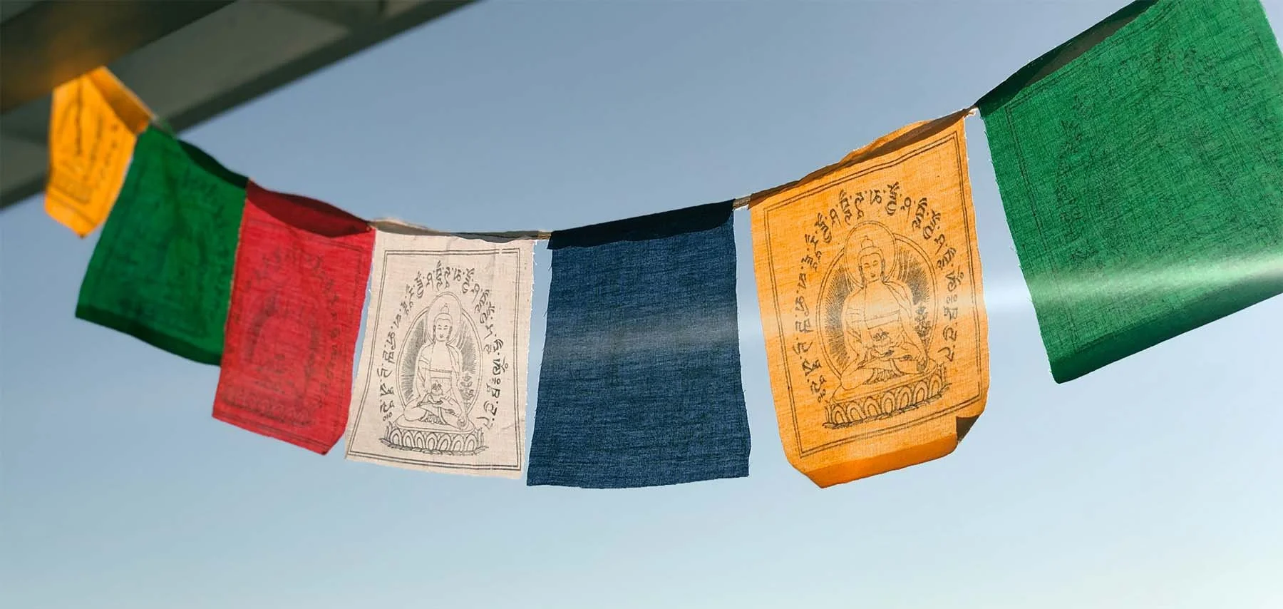 Colorful Tibetan prayer flags with Buddhist symbols and script, hanging outdoors. San Francisco Zen Center