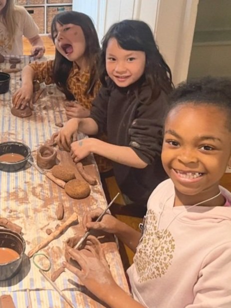 Kids of dirrent ages and skin tones creating with terra cotta clay