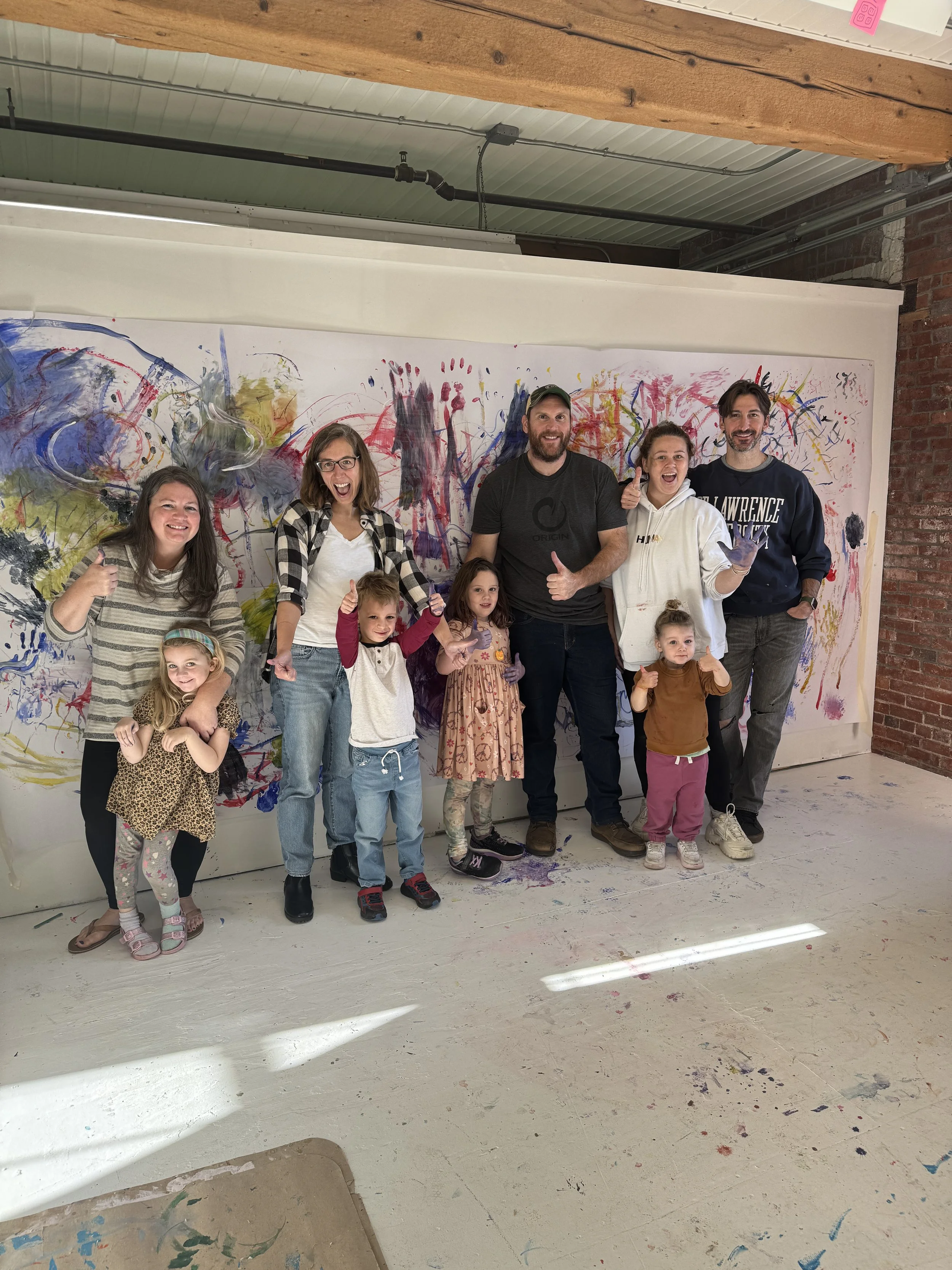 photo pf parents and small children in front or a large abstract painting