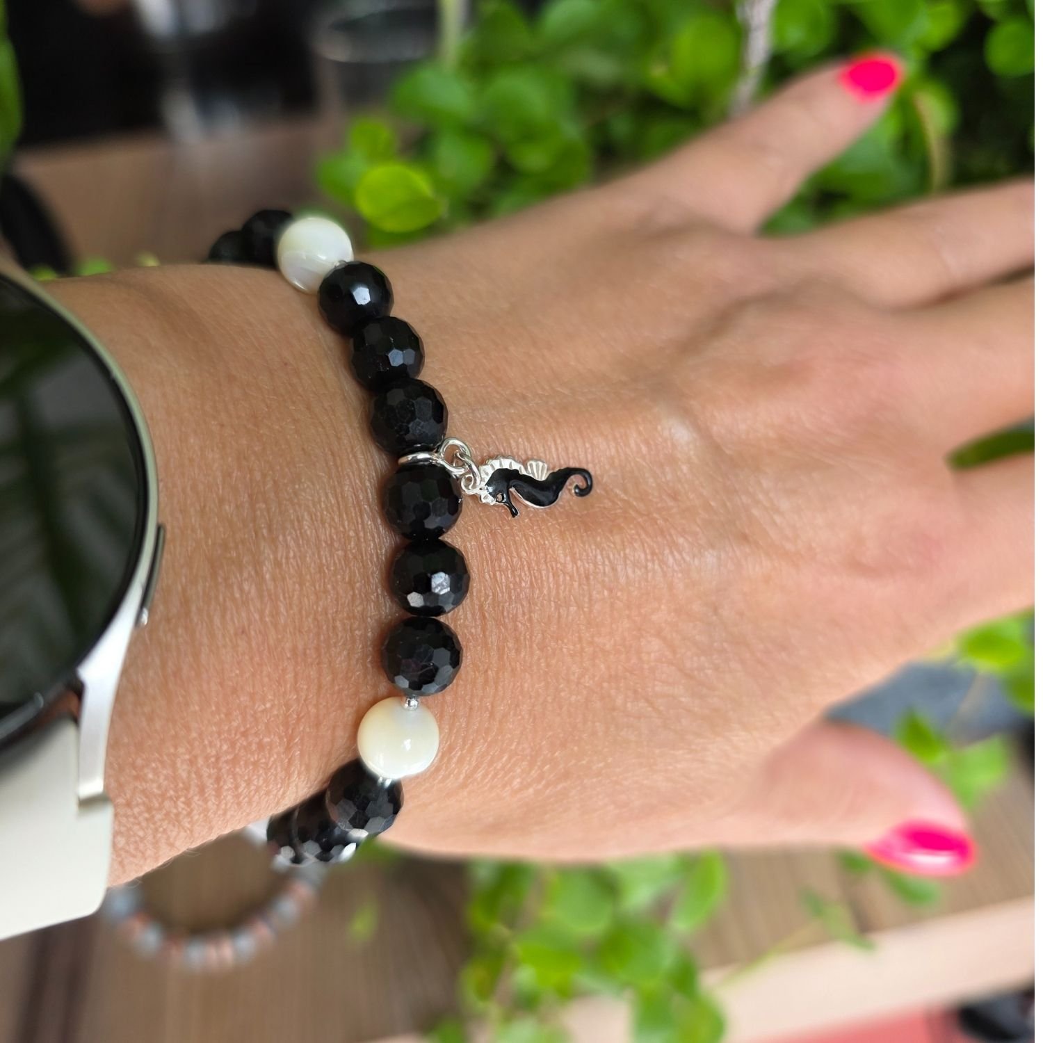 Detailaufnahme des Turmalin und Perlen Armbands am Handgelenk mit Fokus auf den facettierten Turmalin und das glänzende Seepferdchen