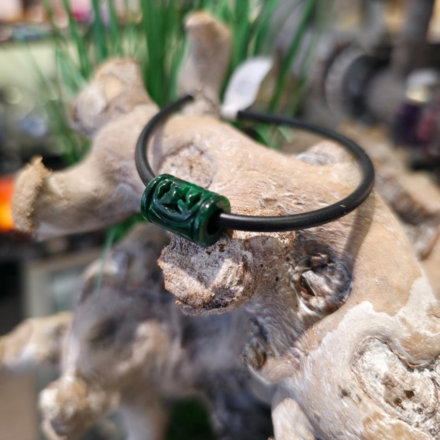 Armband mit handgeschnitztem Burma-Jade-Zylinder auf schwarzem Kautschukband, getragen am Handgelenk, mit 925 Silberverschluss – spiritueller Edelsteinschmuck für Balance und Herzöffnung.