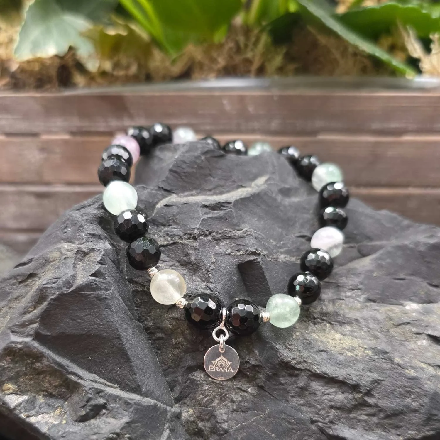 Fluorit-Turmalin-Armband mit Prana 925 Silberanhänger, kombiniert aus schwarzen facettierten Turmalinen und durchscheinenden Fluoritkugeln in zartem Grün, Lila und Weiß – fotografiert auf dunklem (5).jpg