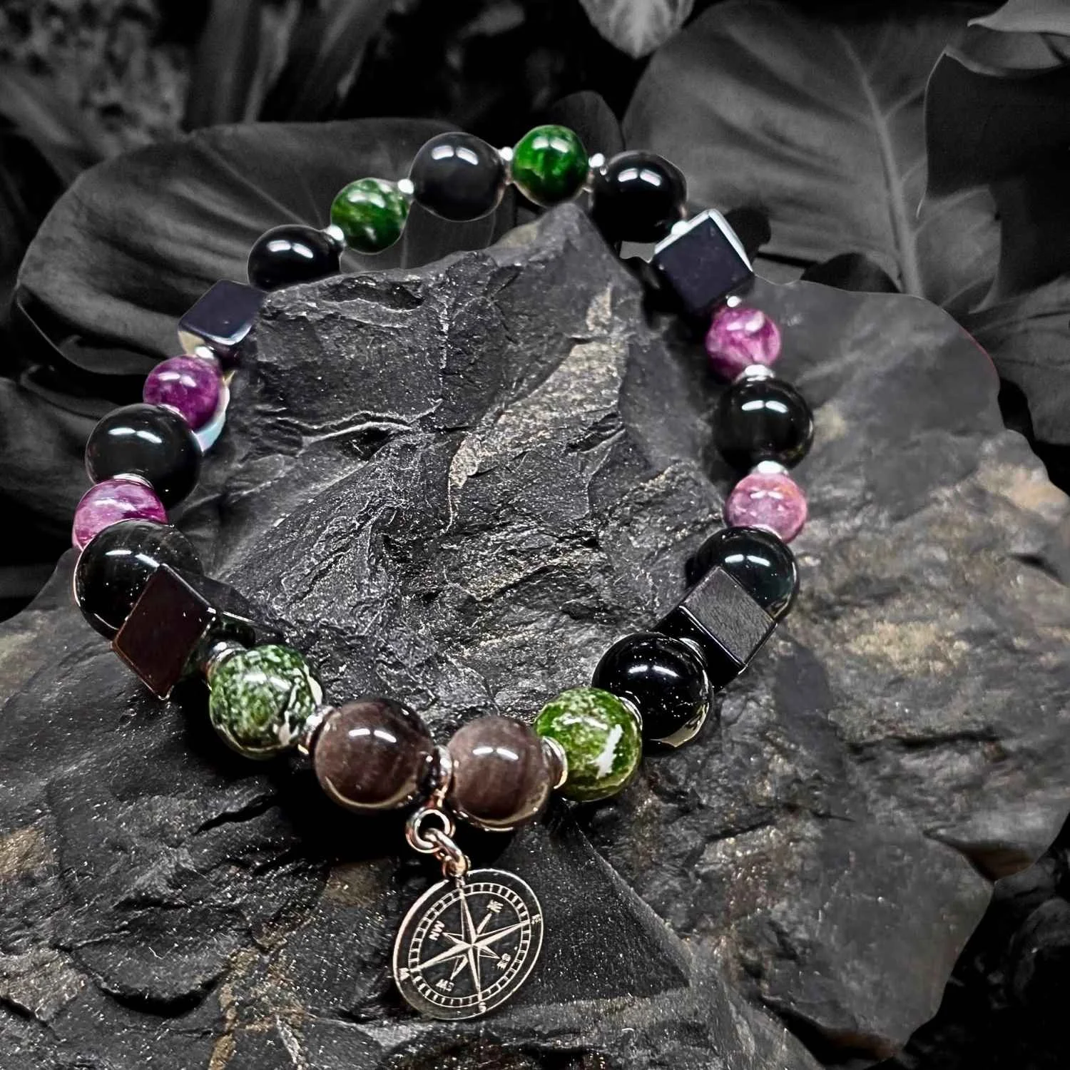Männerarmband aus Obsidian, Lepidolith, Hämatit und Chromdiopsid mit 925 Silber Kompass-Anhänger auf dunklem Naturstein
