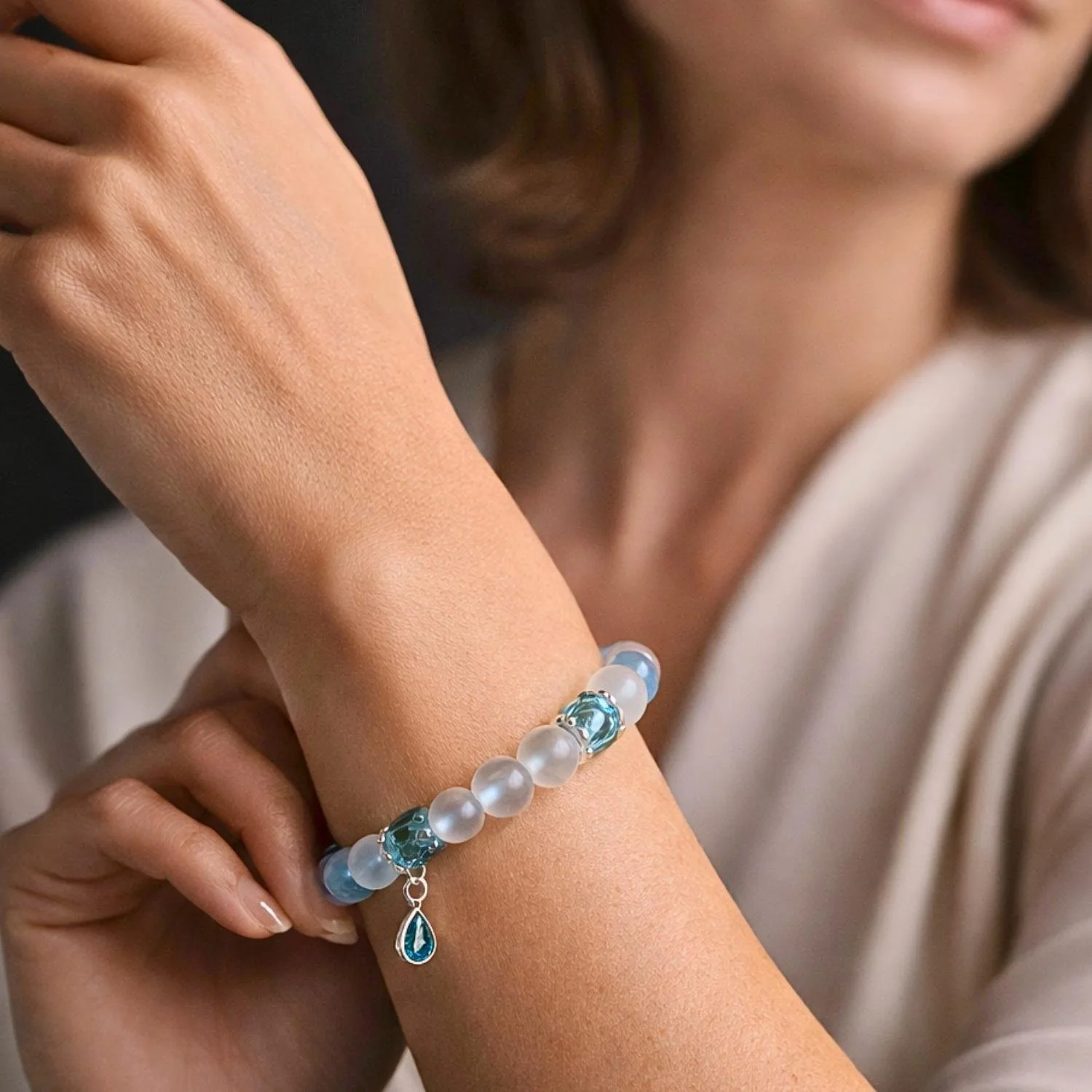 Damenarmband aus Aqua Aura, Bergkristall, Blautopas, Muranoglas und 925 Silber am Handgelenk mit zarter, lichtvoller Ausstrahlung in eleganter Nahaufnahme