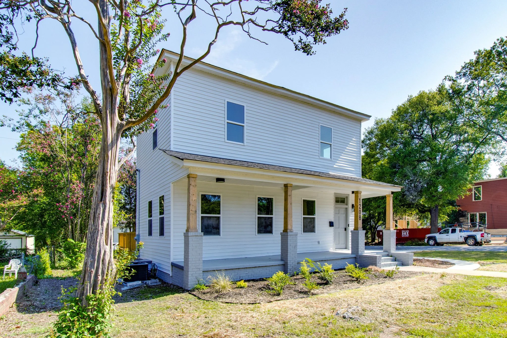 Two-story white house with a front porch and surrounding trees.
