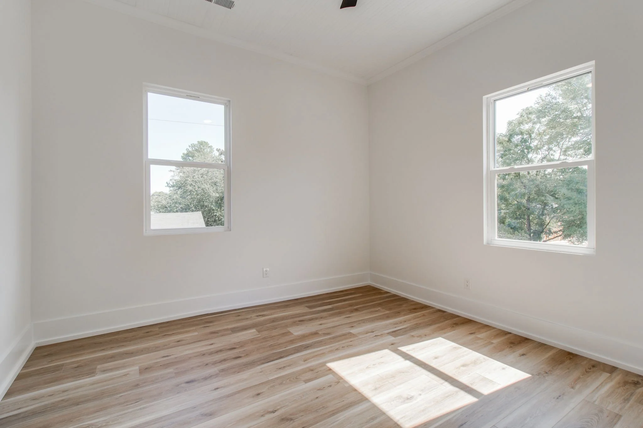 Empty room with two windows and wood floor