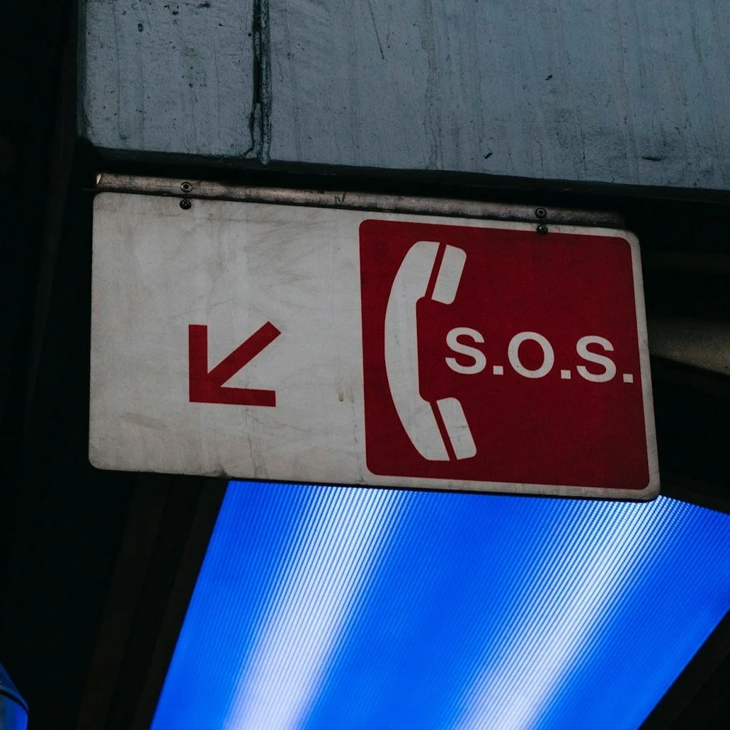 Sign with a red background and a white telephone icon, displaying 'S.O.S.' and an arrow pointing downward.