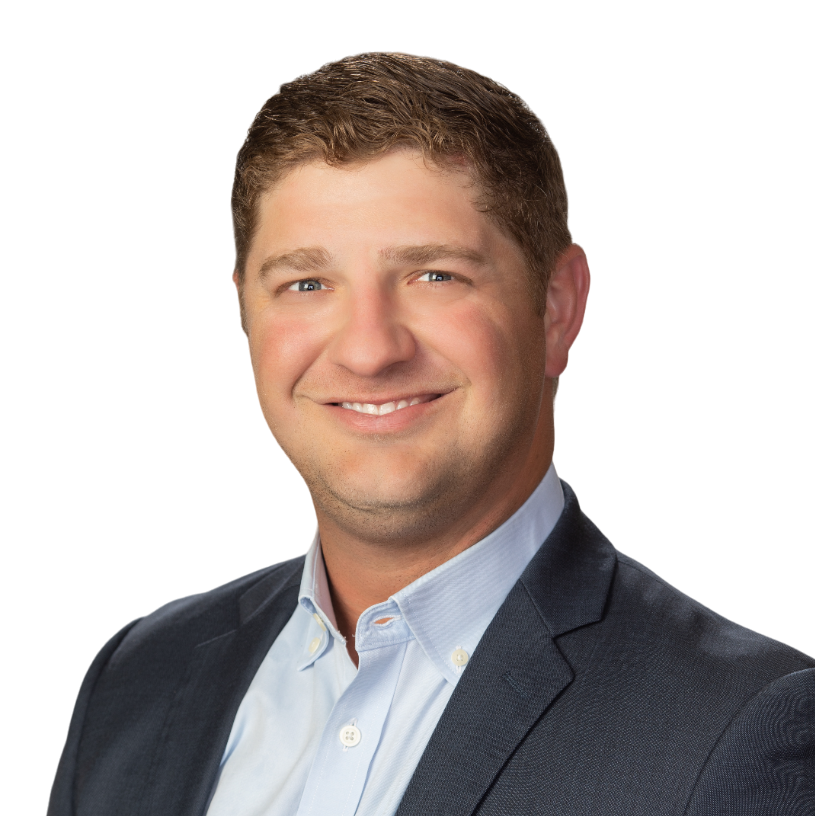 Professional headshot of a man with short brown hair wearing a dark suit jacket and light blue shirt, smiling against a white background.
