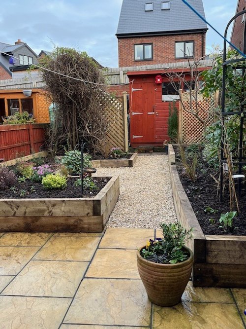 A beautifully designed garden with lush greenery, vibrant flowers, and a serene seating area. Thoughtfully landscaped with a mix of seasonal plants, textured foliage, and natural stone pathways, creating a tranquil outdoor retreat.