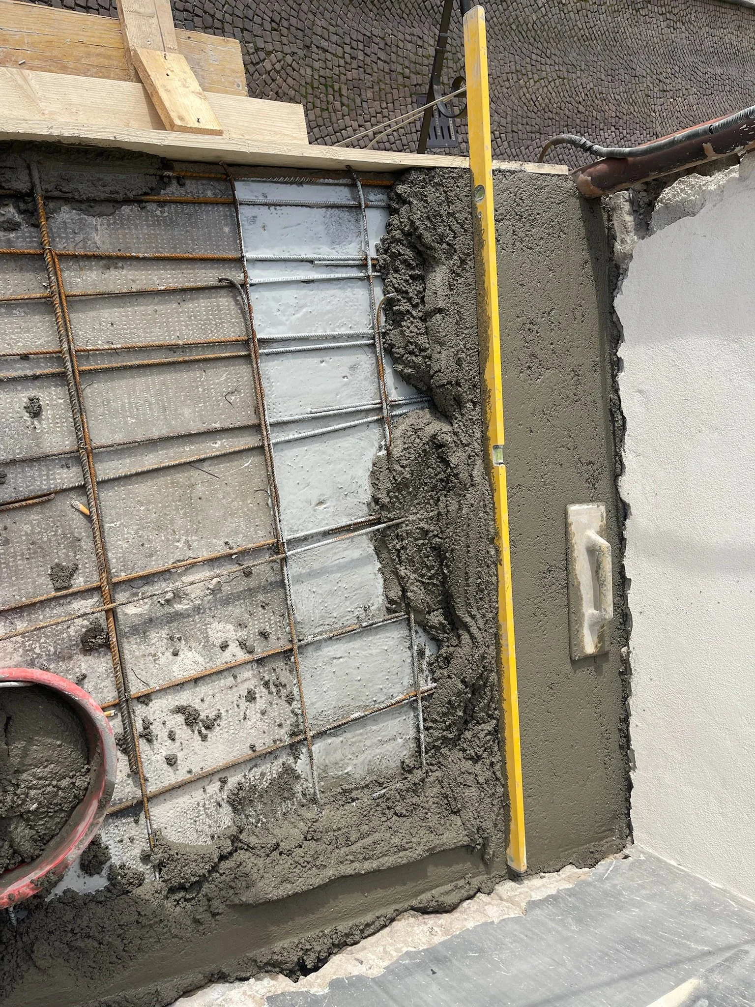 Lavori di costruzione con recinzione e puntello in un muro con armature di ferro e vero cemento.