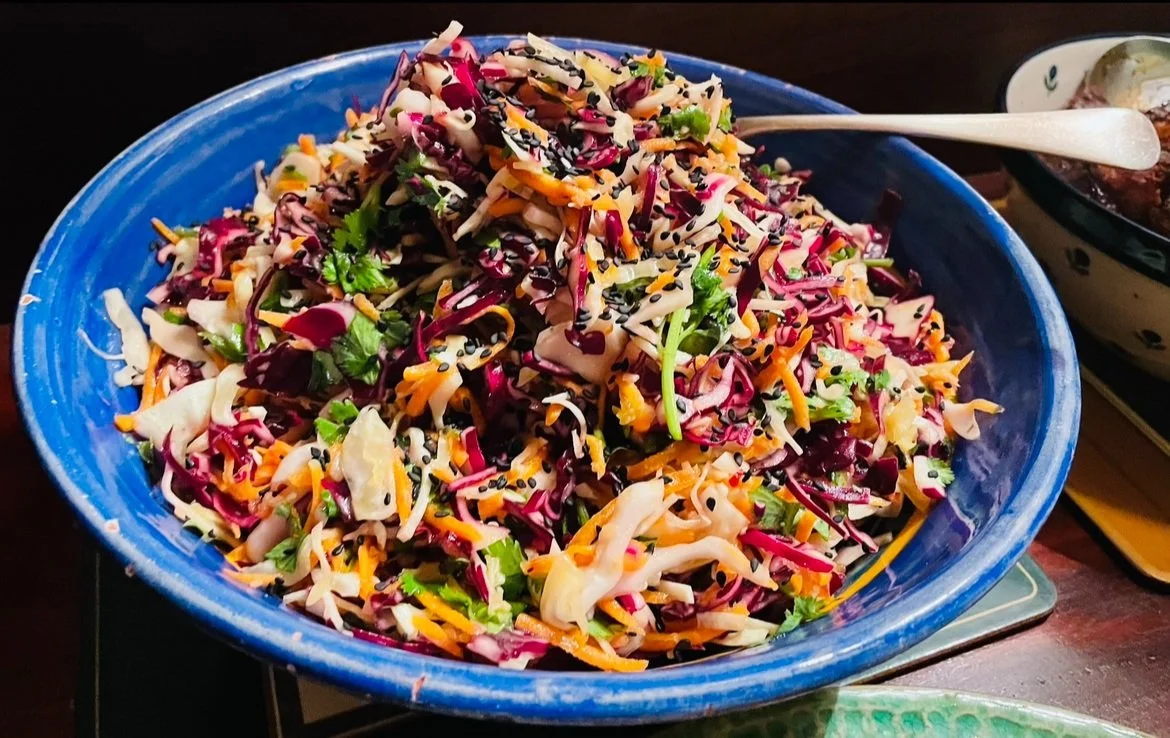 Colorful coleslaw salad in bowl with black sesame seeds.
