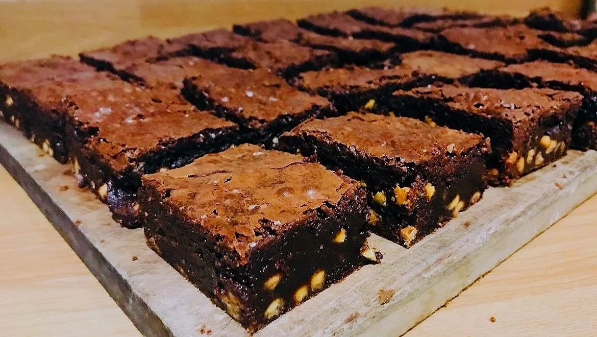 Close-up of chocolate brownies with nuts on a wooden board.