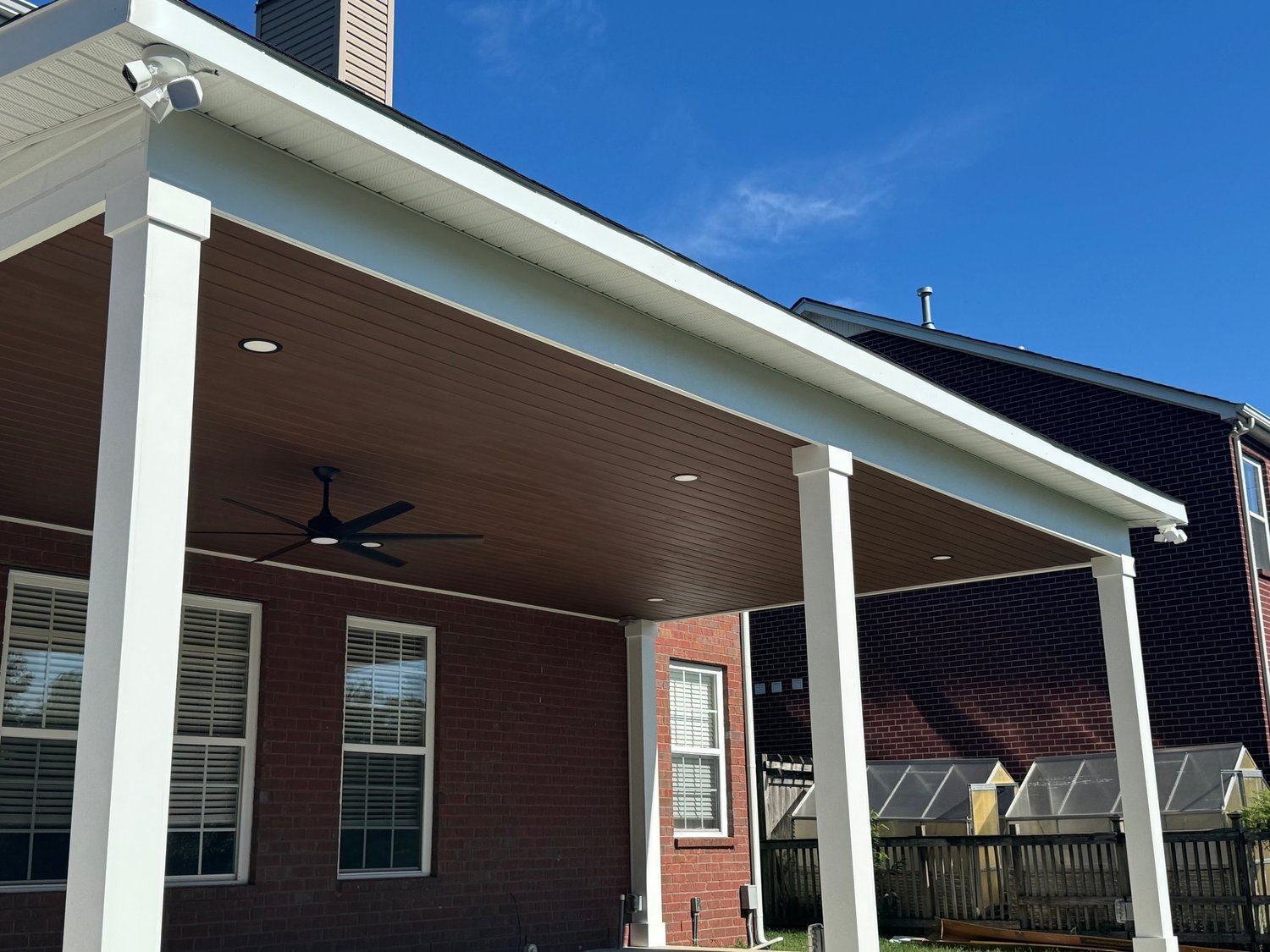 Covered outdoor living space with white columns, ceiling fan, and finished ceiling