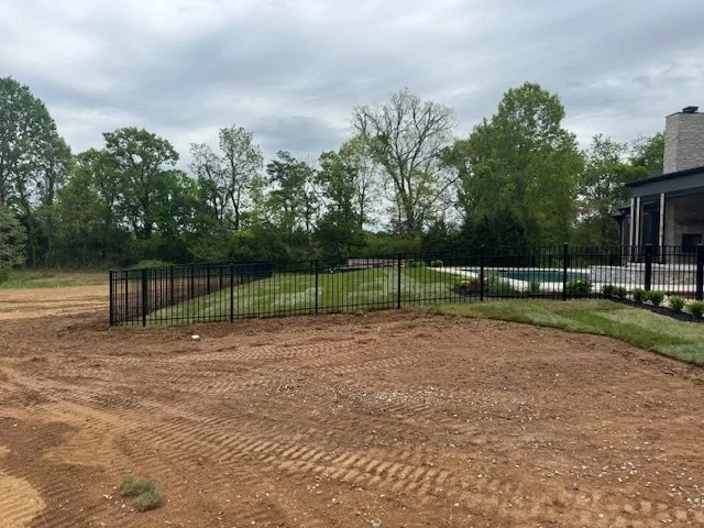 Black metal fence line following the grade of a freshly graded lawn