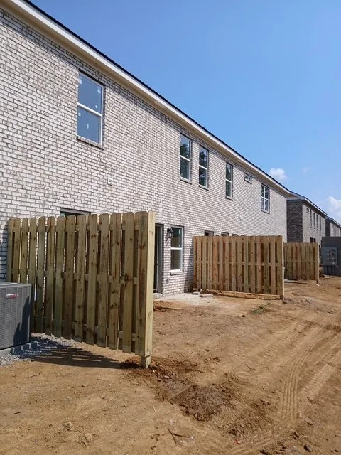 Wood privacy fence with a matching swing gate installed beside a brick home