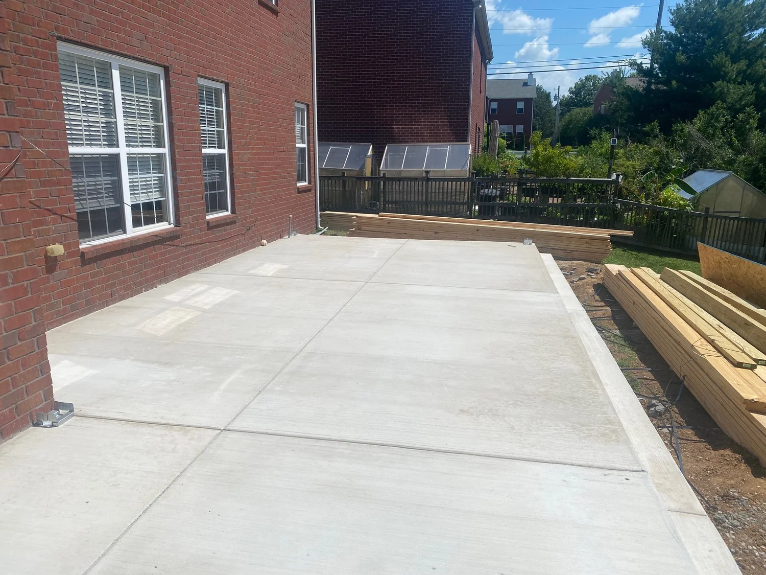 Large finished concrete patio poured against the back of a brick home