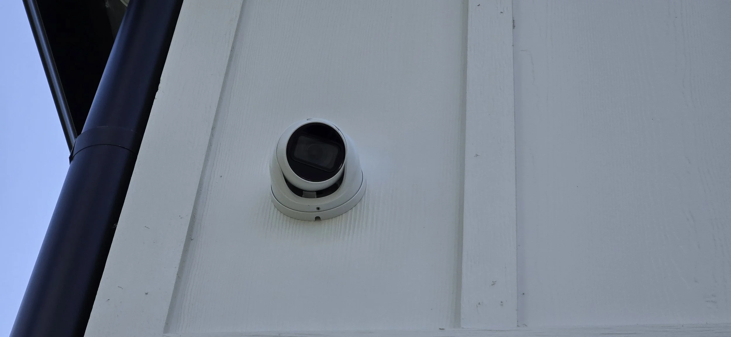 Close-up of a dome security camera mounted on exterior siding