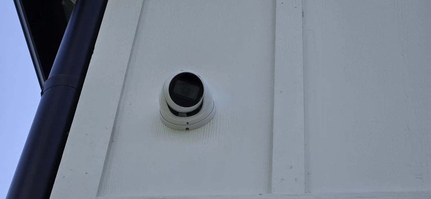 Close-up of a dome security camera mounted on exterior siding