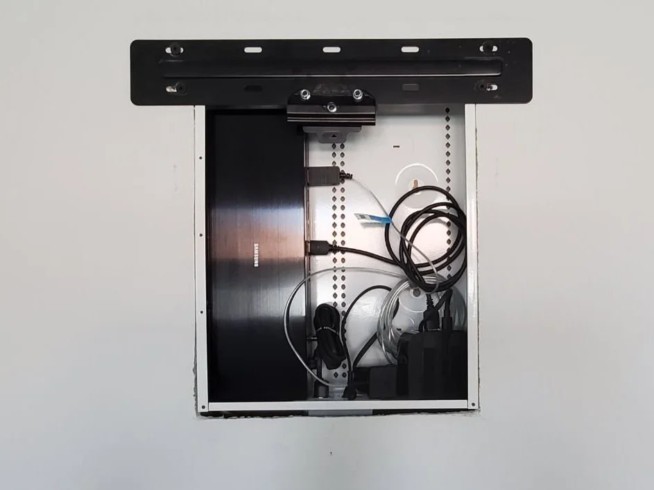 Recessed wall enclosure holding TV equipment behind a wall-mounted TV
