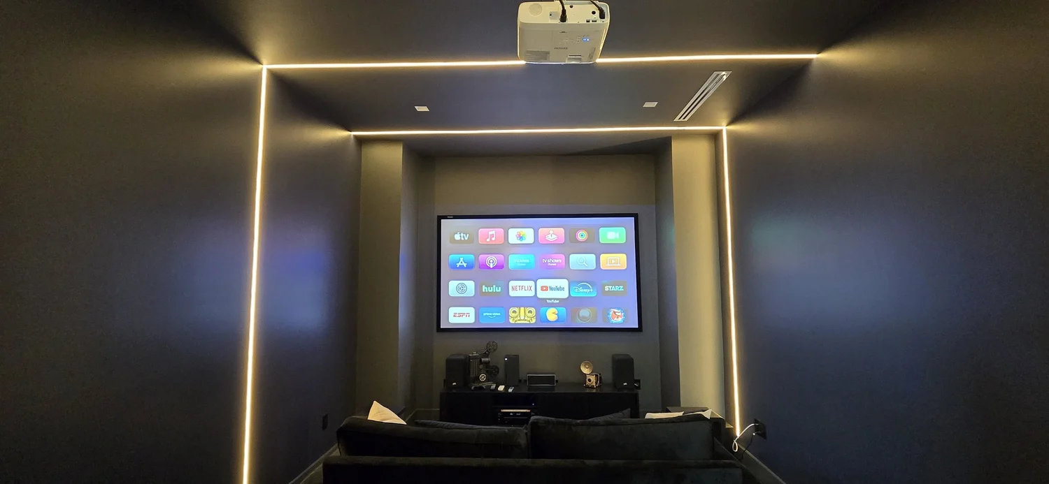 Black-painted home theater with white LED strip lighting along the walls and ceiling