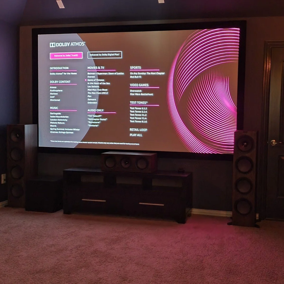 Home theater with lit projection screen and tower speakers