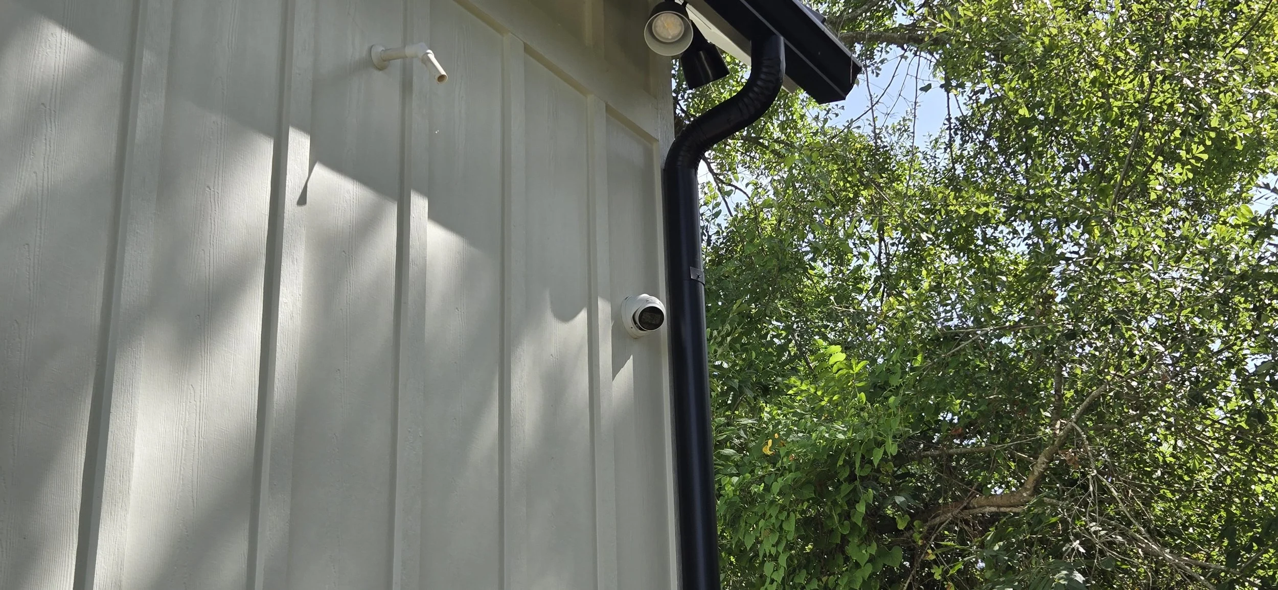 Discreet security camera blended into board-and-batten siding on an estate home