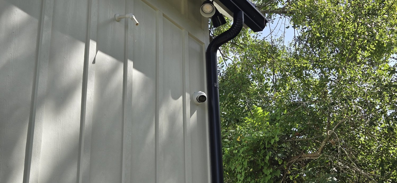 Discreet security camera blended into board-and-batten siding on an estate home