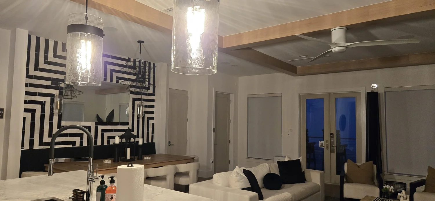 Open kitchen, dining and living area with glass pendant lights and wood ceiling beams