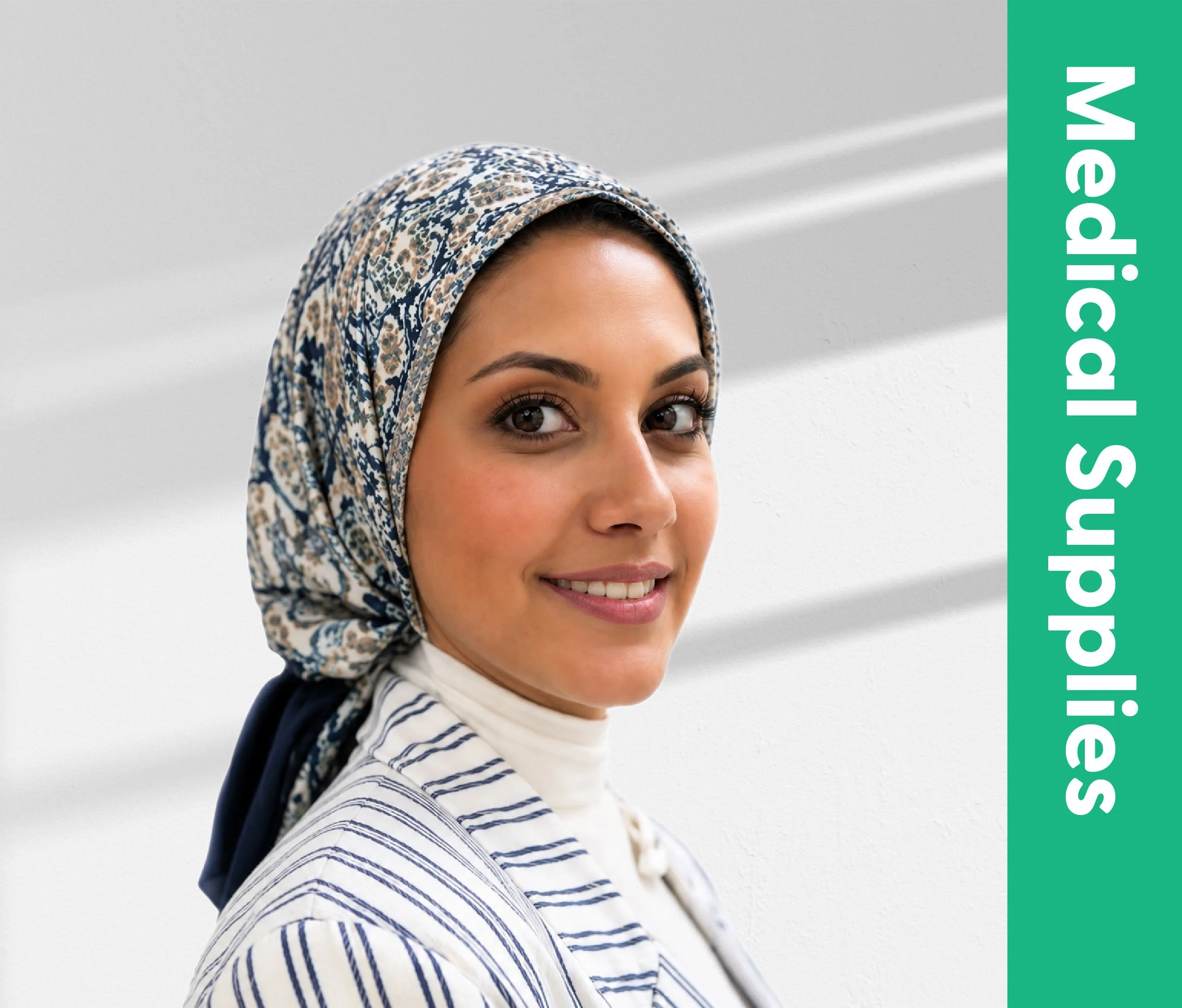 Close-up of a woman's face with brown eyes, smiling, wearing a patterned headscarf and a striped shirt, against a plain light background.