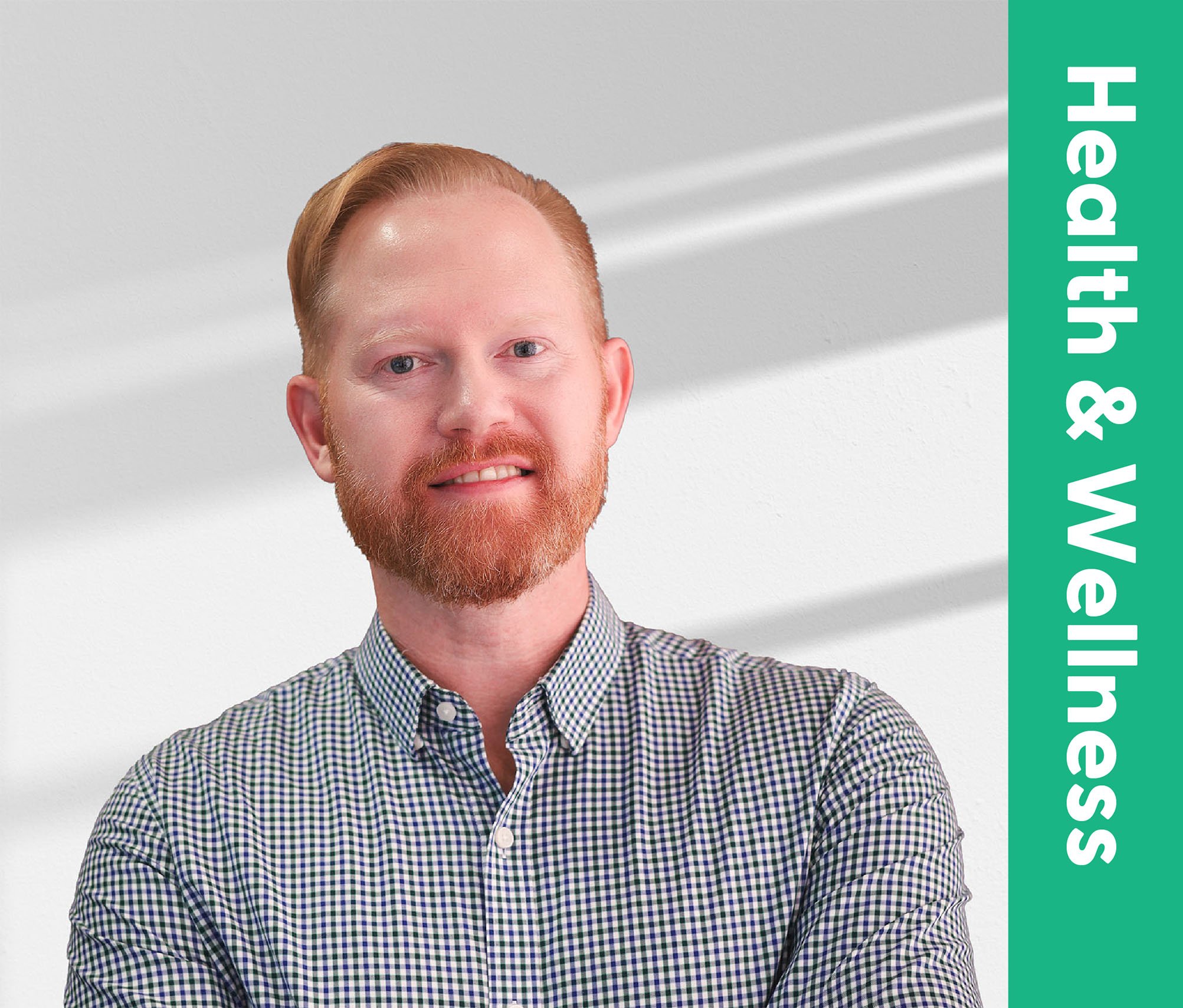 A man with red hair and a red beard wearing a checkered shirt. Part of a green banner with white text is visible on the right side.