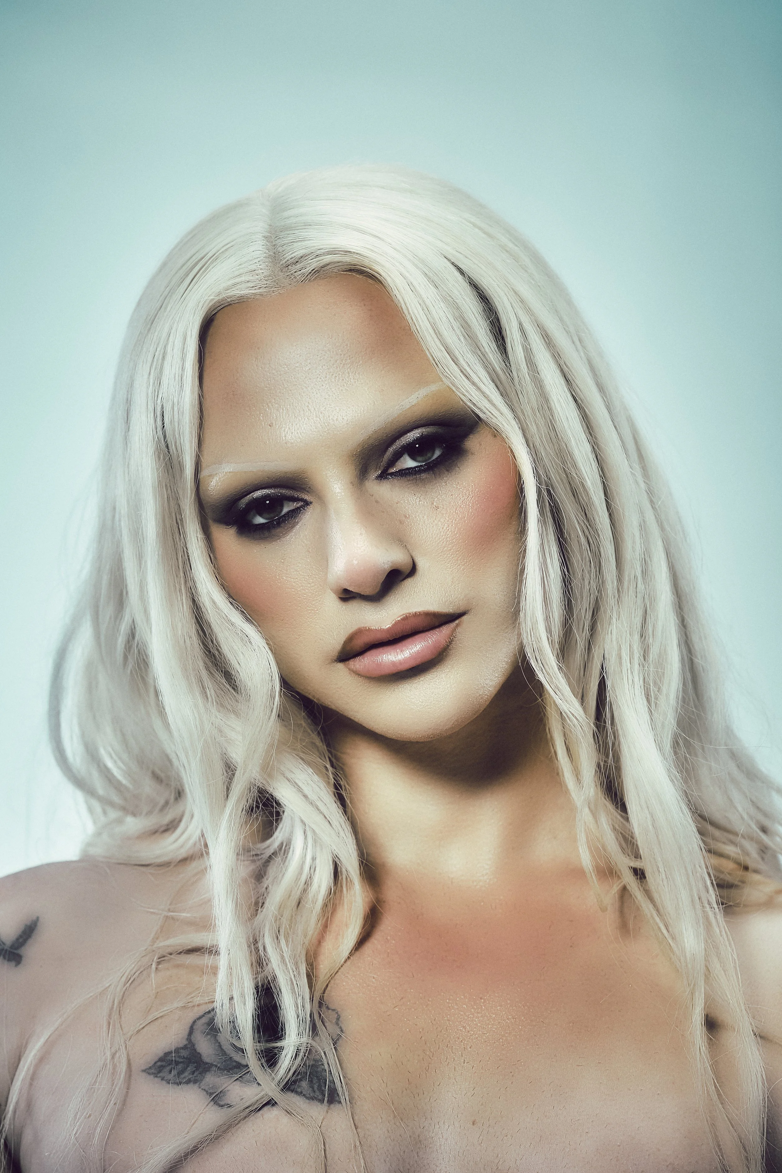 close up of blonde woman with graphic pink makeup, big eyelashes, earrings and big beige lips