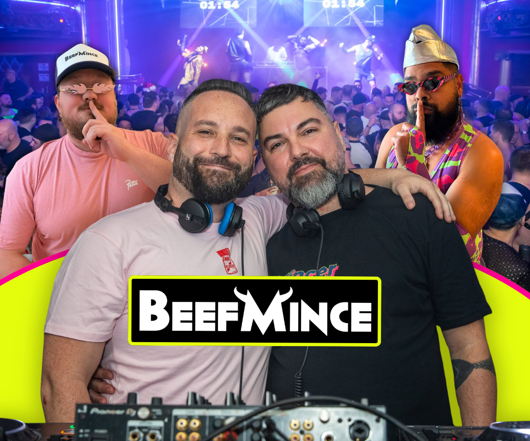 A club night with two DJs at the front on the decks, and a crowd with blue lighting in the background behind them.  