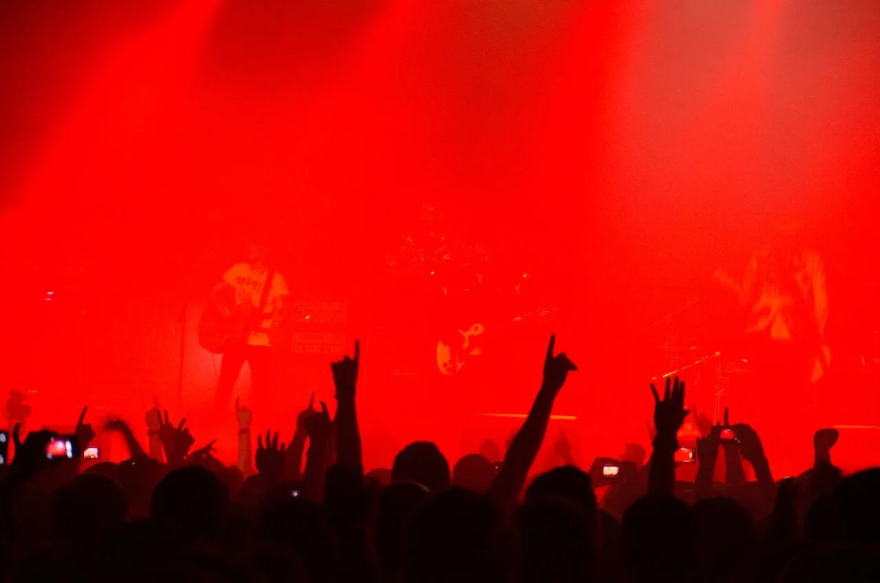 Live music crowd with raised hands under intense red stage lighting