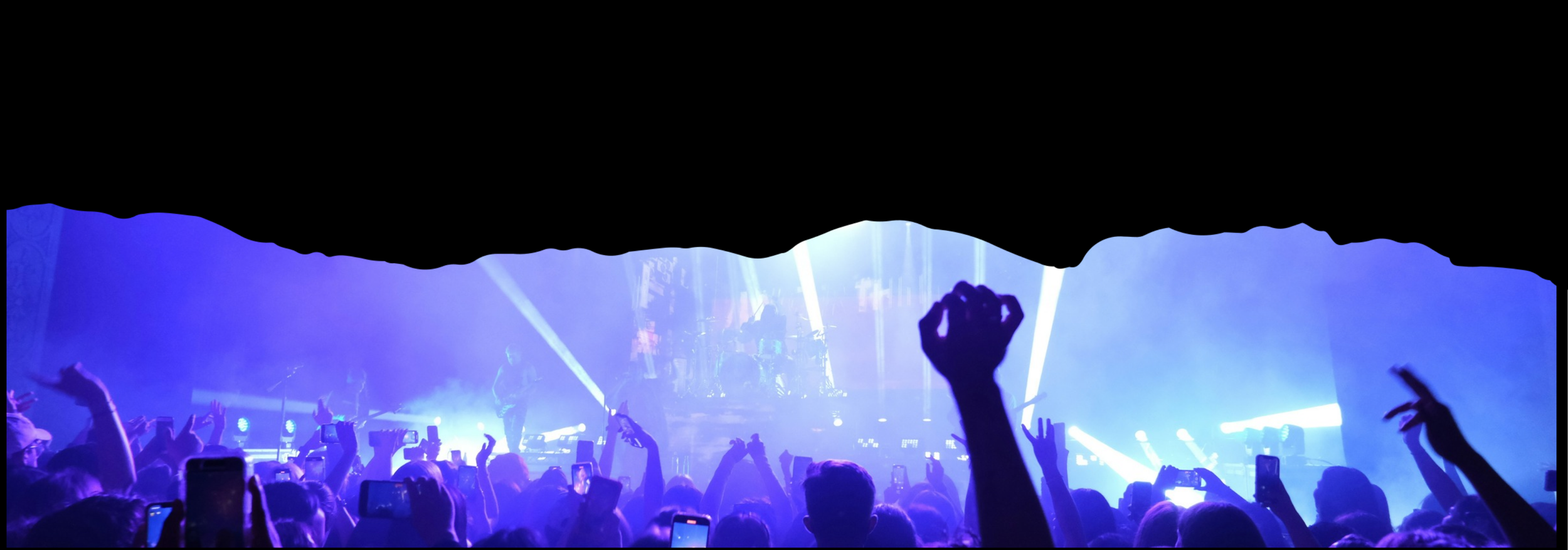 Live music crowd watching a concert under blue stage lighting