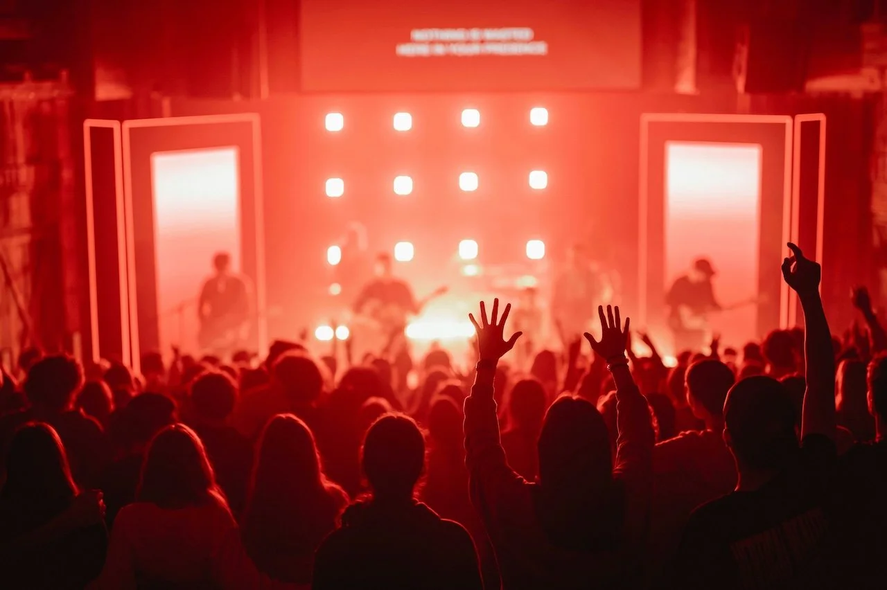 Live music audience with raised hands watching a band perform on stage