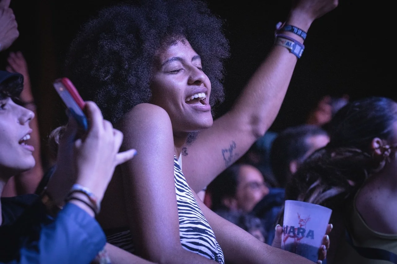 Live music fan enjoying live music with one arm raised in the crowd