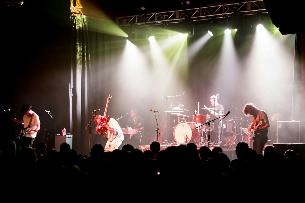 Guitarist performing live on stage in front of a crowd