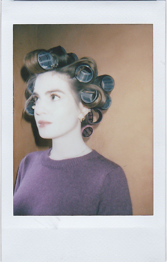 Person with hair curlers and a purple sweater.