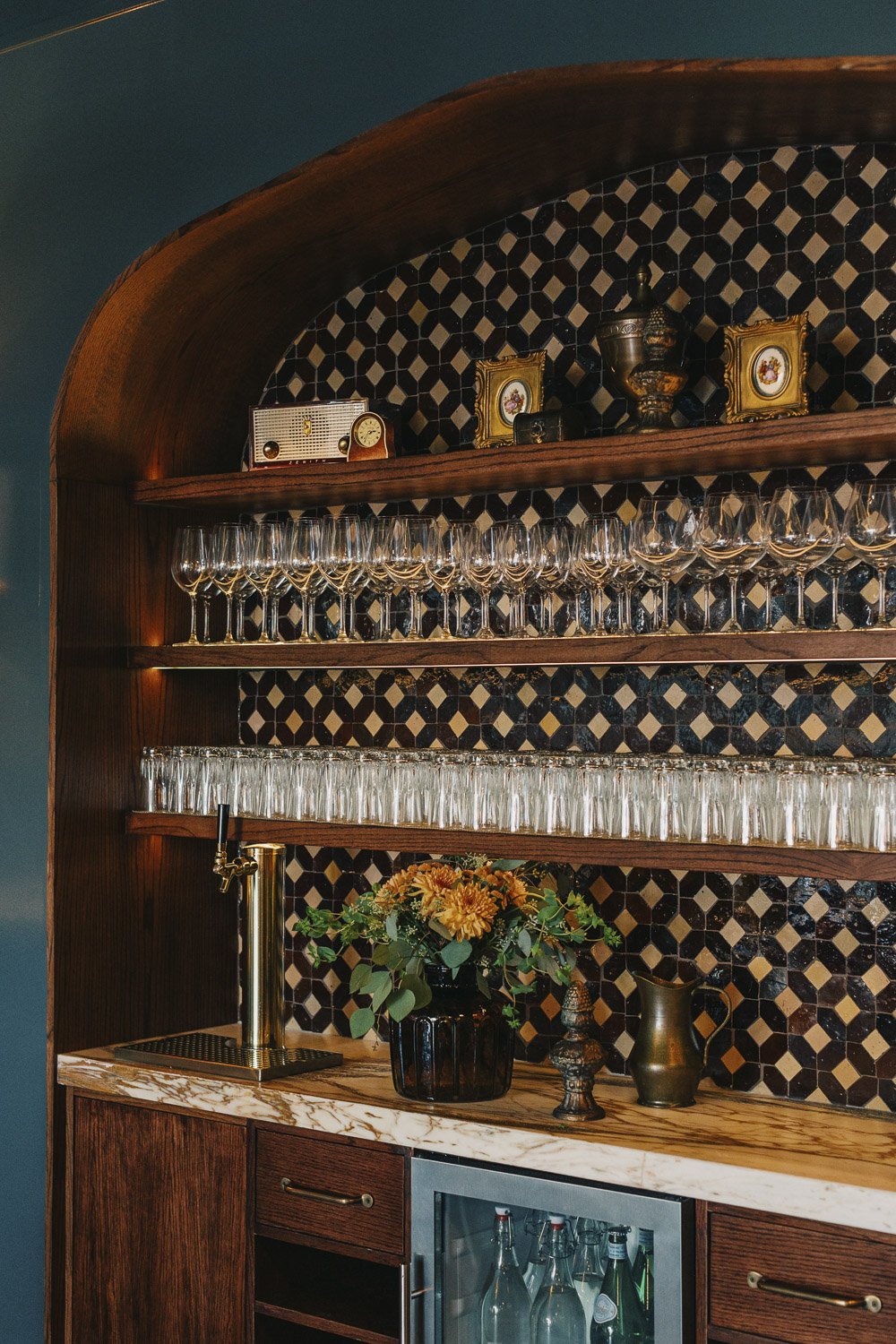Vintage-inspired service station with handmade tile, custom wood shelving, marble countertop, and antiques