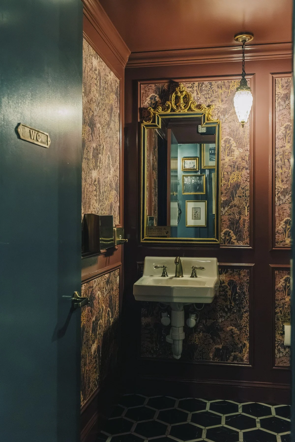 Vintage-inspired bathroom with inset wallpaper, vintage mirror, and pendant light