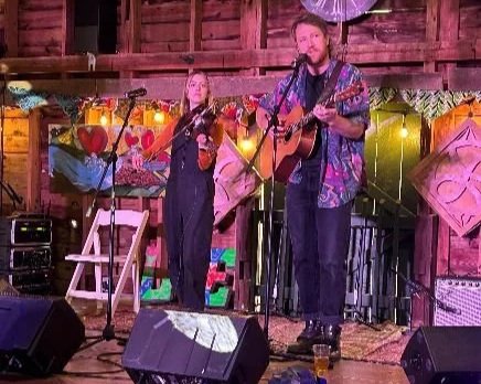 A fiddler and a guitarist perform onstage at the LEAF Festival Barn.