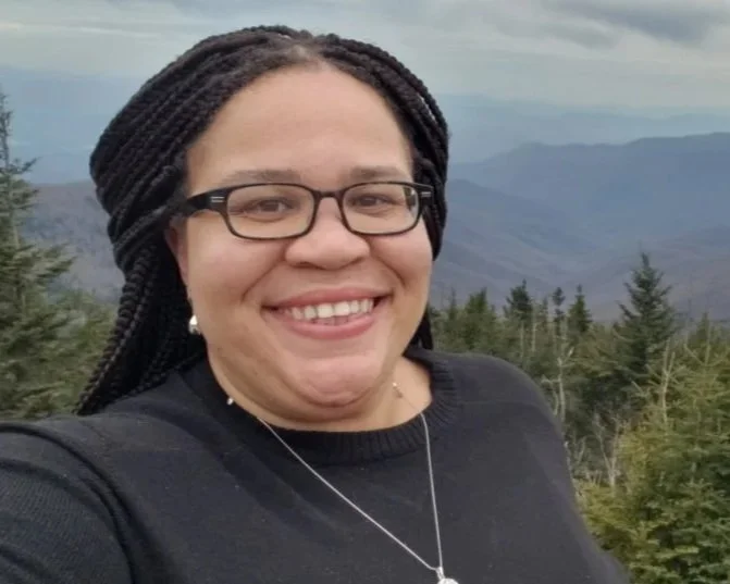 Author Latria Graham is seen in front of a backdrop of green mountain peaks.