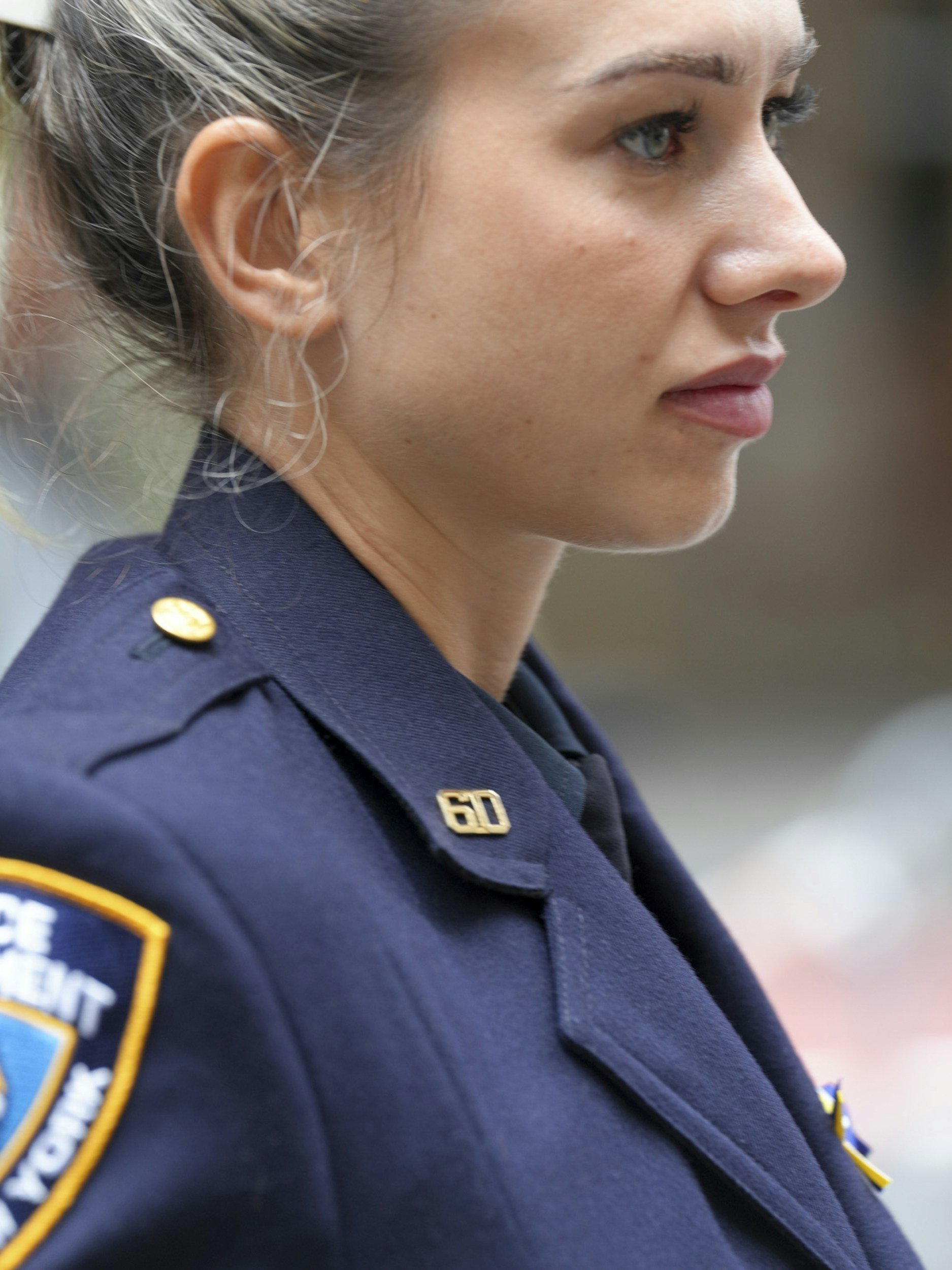 Close-up of a female police officer in uniform, showing her face in profile.